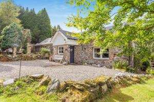 an exterior view of a stone house with a gravel driveway at 1 Bed in Callander oc-pe173 in Strathyre