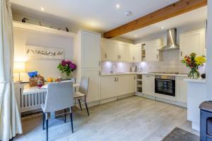 a kitchen with white cabinets and a table and chairs at 1 Bed in Callander oc-pe173 in Strathyre