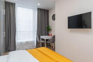 a bedroom with a bed and a table and a television at Видові Апарти на Озеро поруч з метро Позняки Харківська Ревуцького in Kyiv