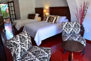 a hotel room with two beds and a chair at Collection O Casa Bella Hotel Boutique, Cabo San Lucas in Cabo San Lucas
