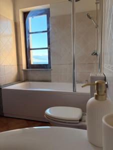a bathroom with a tub and a toilet and a window at Liber Barbaresco House in Barbaresco +31 photos