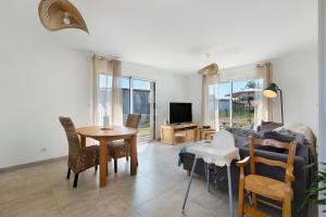 a living room with a couch and a table and chairs at Maison entre foret et mer in Millebosc