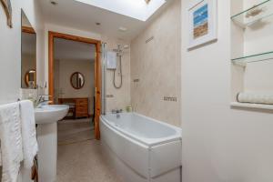a white bathroom with a tub and a sink at Mariners Cottage - Elie in Elie +23 photos