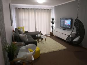 a living room with a couch and a tv at Place At Menlyn in Pretoria