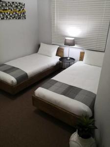 two beds in a room with two tables and a lamp at Place At Menlyn in Pretoria +29 photos
