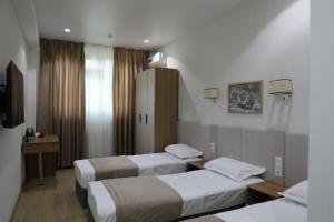 a hotel room with three beds and a television at Chotqol Sanatorium in G‘azalkent