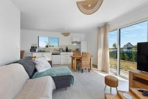 a living room with a couch and a kitchen at Maison entre foret et mer in Millebosc