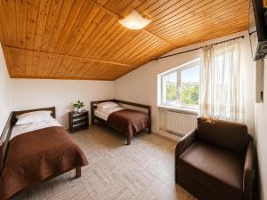 a bedroom with two beds and a chair and a window at Family ЛюКс in Kamianets-Podilskyi