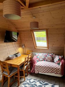 a room with a table and a couch and a table and chair at Squirrel Glamping Pod in Leighton