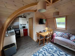 a kitchen and a living room with a table in a cabin at Squirrel Glamping Pod in Leighton