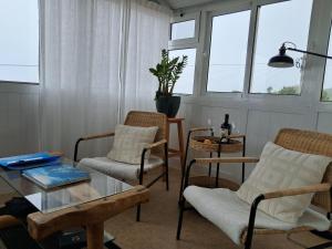 a living room with chairs and a table and windows at Casa Vida Alegre in Prazeres