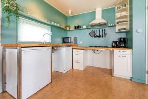 a kitchen with white cabinets and a blue wall at Luwte aan het Lauwersmeer, Friesland in Anjum +11 photos