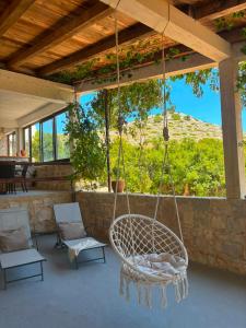 a porch with a swing and chairs on a patio at Seafront Villa in Kornati Private Terrace and Direct Beach Access in Kornati