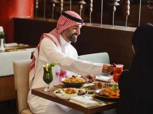 a man sitting at a table with plates of food at Mercure Makkah Aziziah in Mecca