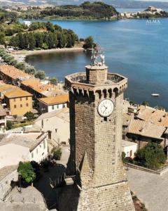 a tower with a clock on it next to the water at Alma Capodimonte Lake chalet in Capodimonte