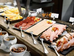 a buffet with many different types of meats and cheese at Mercure Szekesfehervar Magyar Kiraly in Székesfehérvár