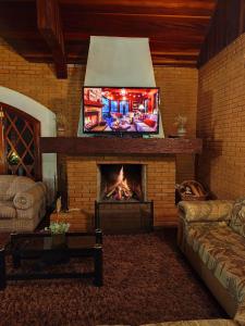 a living room with a fireplace with a flat screen tv at Refugio maná in Campos do Jordão