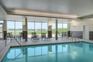 a swimming pool with chairs and tables and windows at Fairfield by Marriott Inn & Suites Mattoon in Mattoon