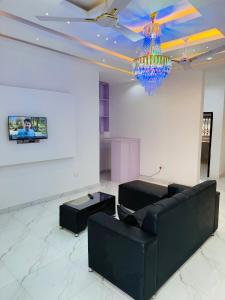 a living room with a black couch and a chandelier at Pebview 2 Bed Apartment in Kpone