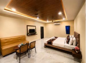 a bedroom with a bed and a table and a desk at Hotel Sky Palace Airport Zone in Hyderabad