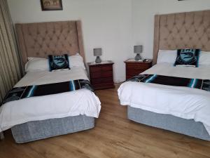 a bedroom with two beds and two night stands at Martha's Guesthouse in Gqeberha +29 photos