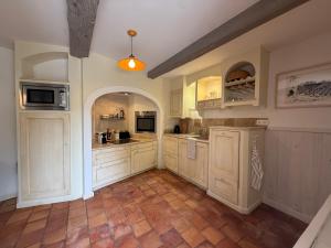 a large kitchen with white cabinets and a tile floor at Chez Marie in Grignan