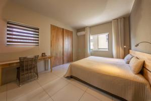 a bedroom with a bed and a desk and a window at Beachfront villa by M&H in Tamarin