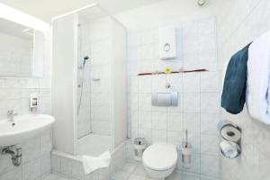 a white bathroom with a toilet and a shower at Hotel Dortmund City in Dortmund