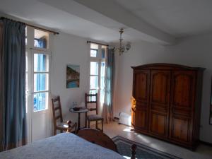 um quarto com um armário de madeira e 2 janelas em Poppys Chambres d'Hotes em Céret