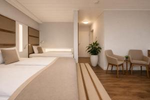 a hotel room with two beds and a table and chairs at Hotel Dortmund City in Dortmund +18 photos
