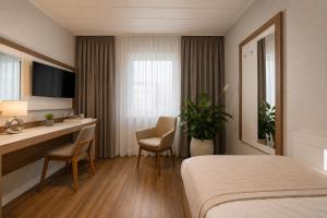 a hotel room with a bed and a desk at Hotel Dortmund City in Dortmund