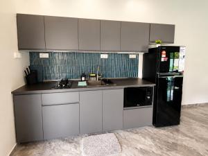 a kitchen with white cabinets and a black refrigerator at Charis Tanjong Jara Villa Emerald in Dungun