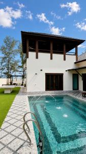 a swimming pool in front of a house at Charis Tanjong Jara Villa Emerald in Dungun