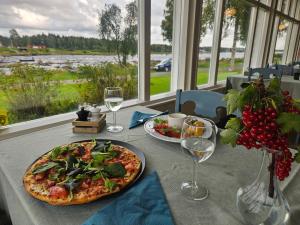 a table with a pizza and glasses of wine at Kukkolaforsen Turist & Konferens in Haparanda