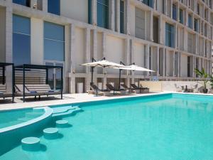 a swimming pool with chairs and umbrellas next to a building at Novotel Riyadh Sahafa in Riyadh