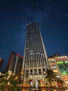 a tall building with lights on it at night at High Clouds Hotel Apartment in Guangzhou