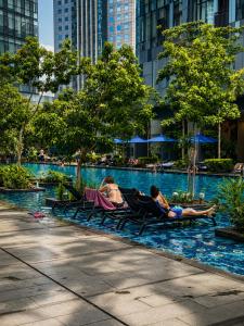 two people laying in lawn chairs in a pool in a city at GOLDEN Services Suites At Star KLCC in Kuala Lumpur