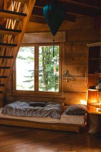 a bed in a wooden room with a window at Bukowica Miła - Dom z sauną w sercu Natury 2000 in Wola Piotrowa