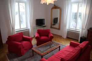 een woonkamer met 2 rode stoelen en een spiegel bij Villa Adrienne in Velden am Wörthersee