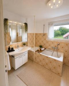 a bathroom with two sinks and a tub and a mirror at Danube Lodge in Hüfingen
