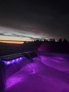 a pool of purple water with a sunset in the background at Domek dwóch jezior z jakuzzi, Chojno pojezierze Brodnickie in Chojno