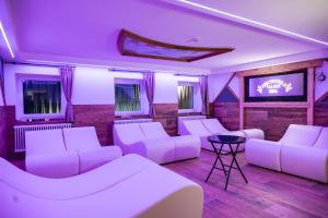 a room with white couches and a flat screen tv at Hotel Orchidea in Passo del Tonale