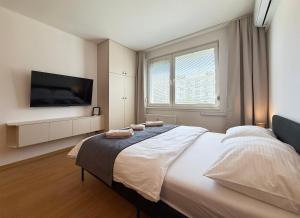 a bedroom with a large bed with a flat screen tv at Cozy Emerald Studio Bratislava in Bratislava