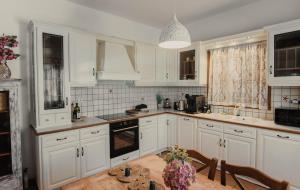a kitchen with white cabinets and a wooden table at Villa Kyma in Aegina