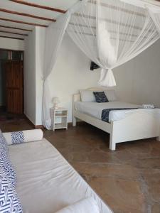 a bedroom with two beds with curtains and a table at Gabsgate Resort Kilifi in Kilifi