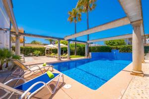 a swimming pool in a resort with chairs and palm trees at Estrel in Can Picafort