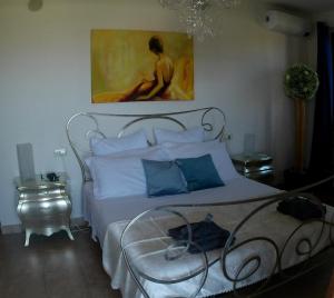 a bedroom with a white bed with a painting on the wall at Locazione Turistica Spaccarotella Vista su Gualdo Cattaneo in Gualdo Cattaneo