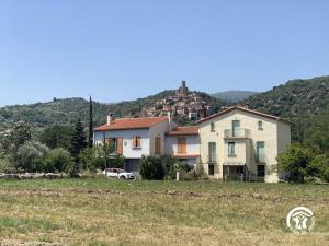 a house in a field with a hill in the background at Mas garrigole in Eus