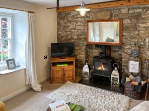 a living room with a stone wall and a fireplace at Lock Heather Cottage in Reeth