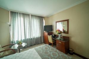 a hotel room with a bed and a table and a mirror at Surmeli Adana Hotel in Adana